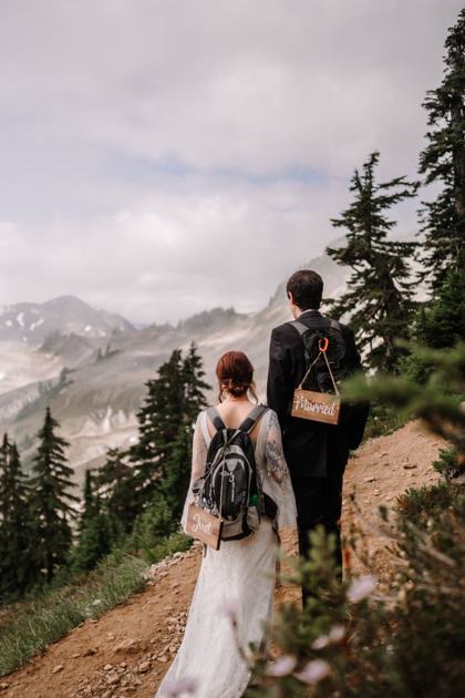Couple hiking an alpine trail in wedding clothes