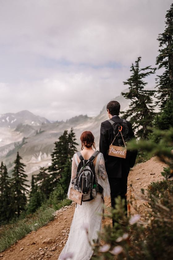 Couple in wedding clothes hiking a high ridge trail