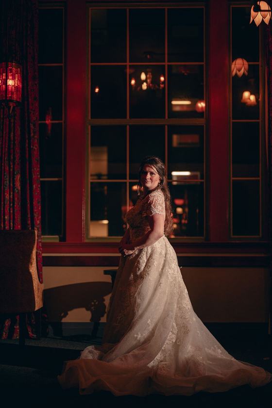 Bride in red light at a tall window