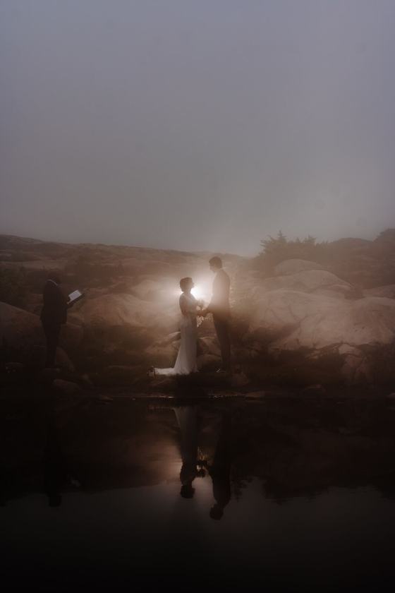 Lantern light beside a still lake under a dark sky