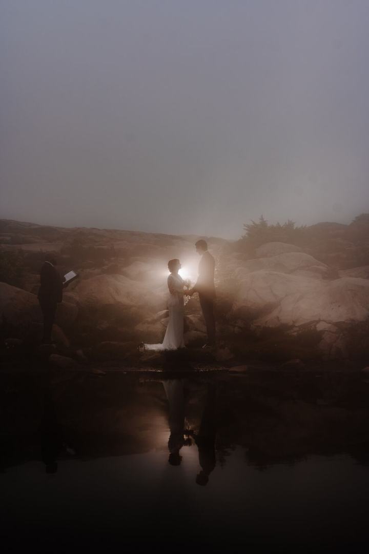 Couple with a lantern beside a dark lake under a night sky
