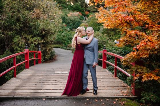 Couple embracing on the red bridge at Kubota Garden