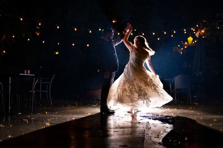 Bride spinning in her dress on a rain-slicked street at night
