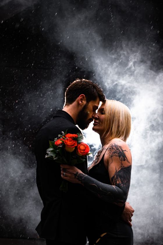 Kiss in rain lit through coloured smoke