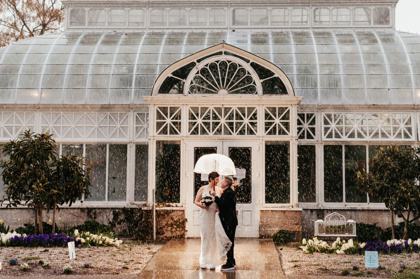 Couple with a clear umbrella outside a glass conservatory