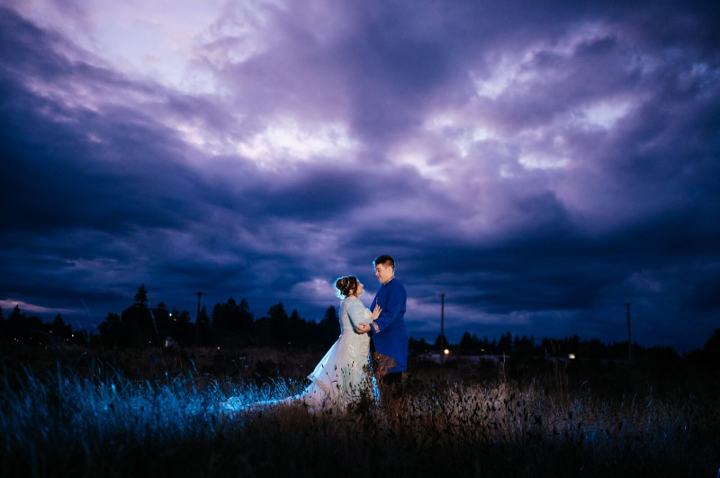 Couple standing in a wide field at twilight