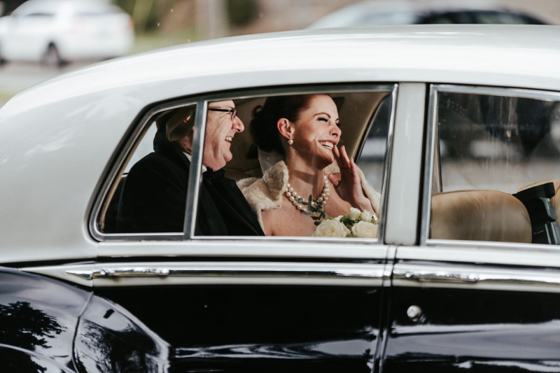 Bride seated in the open door of a vintage car