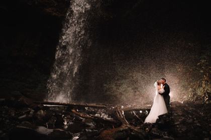 Couple standing in the mist beside a waterfall